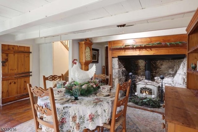 dining space with beam ceiling and a wood stove