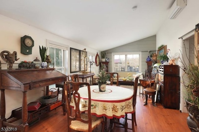 dining area with a wall mounted AC, hardwood / wood-style floors, vaulted ceiling, and a barn door