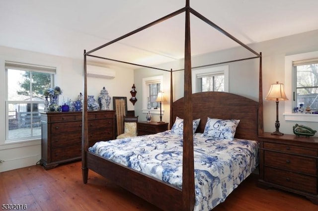 bedroom with hardwood / wood-style floors and a wall mounted air conditioner