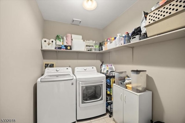 laundry area with washing machine and dryer and light tile patterned floors