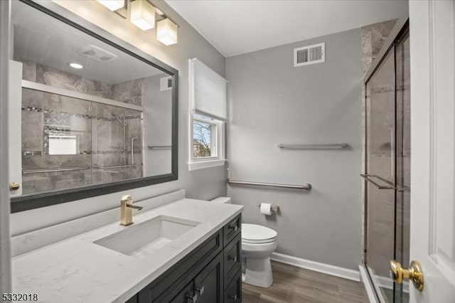 bathroom with toilet, vanity, an enclosed shower, and hardwood / wood-style flooring