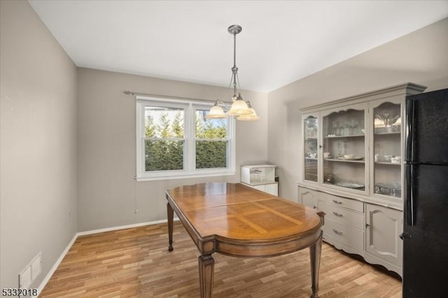 dining space with light hardwood / wood-style floors and an inviting chandelier