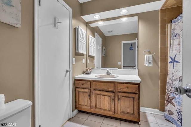 bathroom with tile patterned flooring, vanity, toilet, and walk in shower