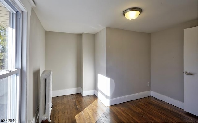 empty room featuring dark wood-type flooring and radiator