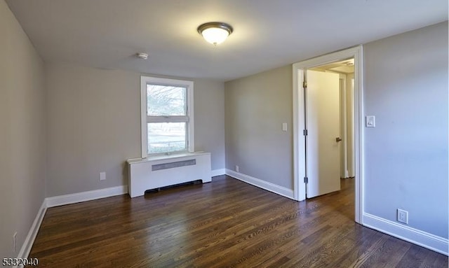 empty room featuring dark hardwood / wood-style floors and radiator