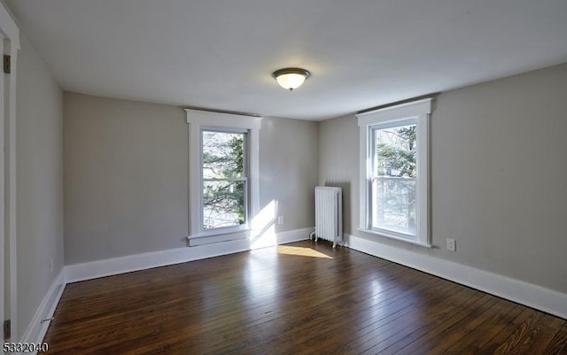 spare room featuring dark hardwood / wood-style flooring and radiator