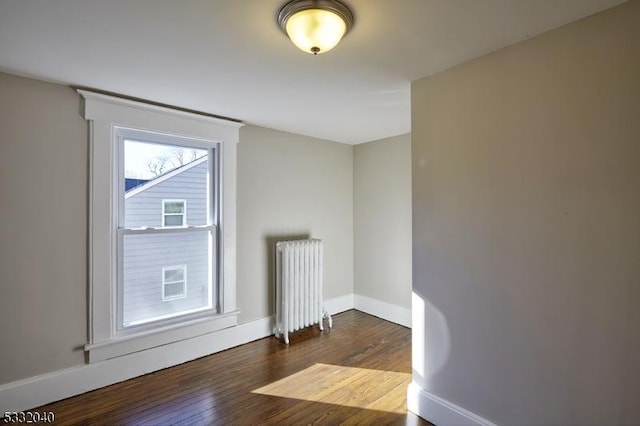 spare room featuring radiator and dark wood-type flooring