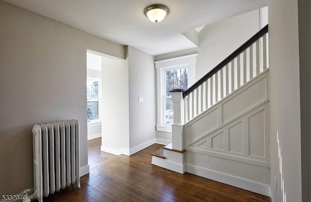 foyer entrance featuring radiator heating unit and dark wood-type flooring