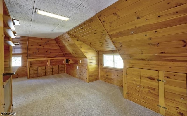 bonus room with lofted ceiling, light carpet, and wooden walls