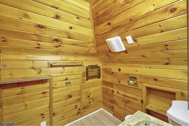 bathroom with wood-type flooring and wooden walls