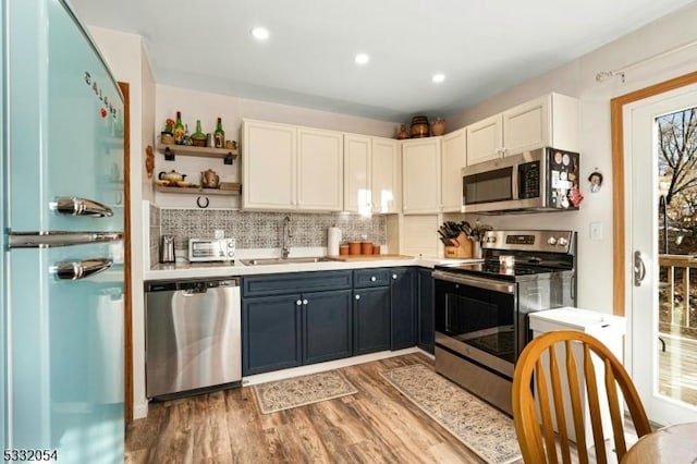 kitchen featuring white cabinetry, sink, stainless steel appliances, tasteful backsplash, and hardwood / wood-style floors