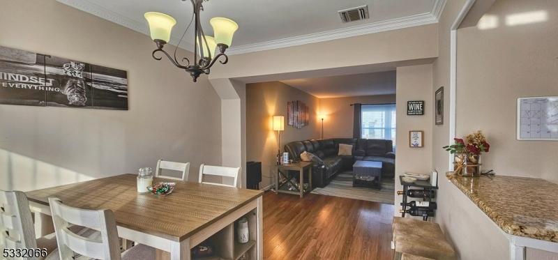 dining space with dark hardwood / wood-style flooring, crown molding, and a chandelier