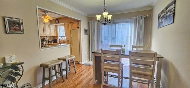 dining room with sink, light wood-type flooring, ceiling fan with notable chandelier, and ornamental molding