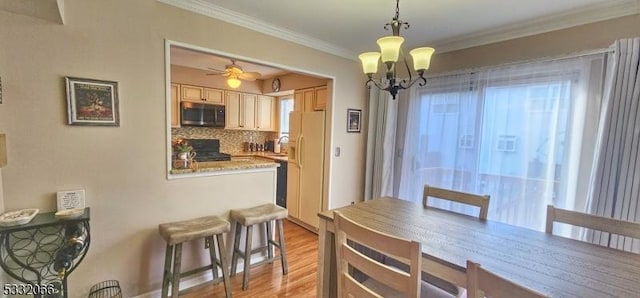 dining space featuring light wood-type flooring, ceiling fan with notable chandelier, plenty of natural light, and ornamental molding