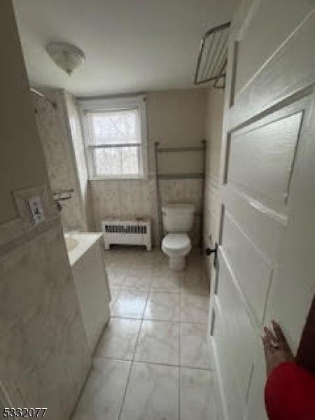 bathroom featuring tile patterned flooring, radiator heating unit, vanity, and toilet