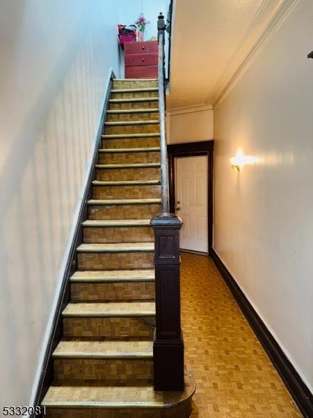 stairs with parquet flooring and ornamental molding