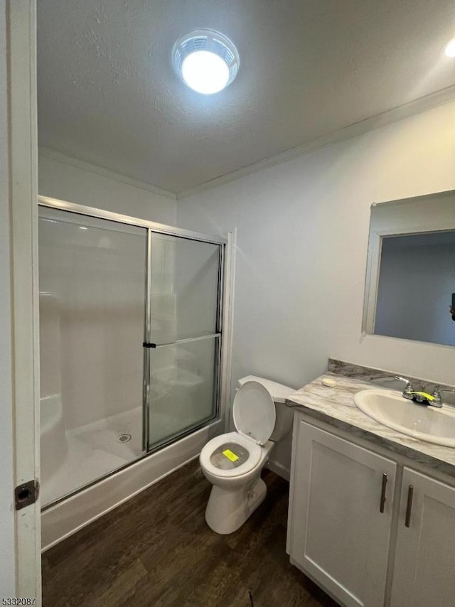 bathroom featuring vanity, toilet, a textured ceiling, an enclosed shower, and wood-type flooring