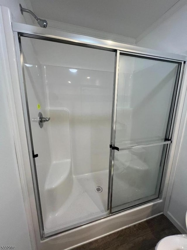 bathroom featuring hardwood / wood-style flooring, toilet, and a shower with shower door