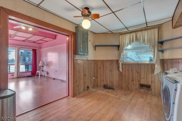 washroom with ceiling fan, hardwood / wood-style flooring, washing machine and clothes dryer, electric panel, and wood walls