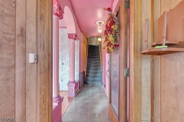 hall with decorative columns and dark tile patterned floors