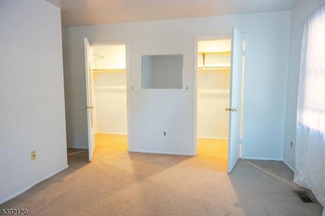 unfurnished bedroom with a closet, a spacious closet, and light carpet