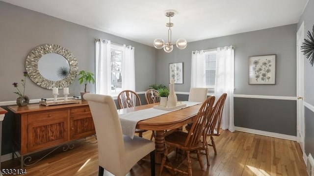 dining space with hardwood / wood-style flooring, a healthy amount of sunlight, and an inviting chandelier