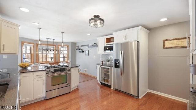 kitchen featuring light hardwood / wood-style floors, appliances with stainless steel finishes, white cabinets, pendant lighting, and wine cooler