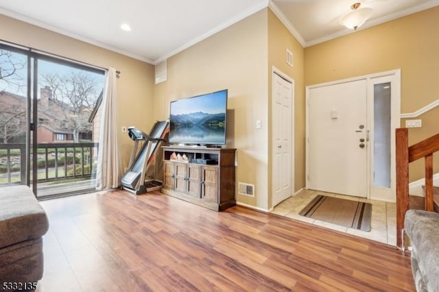 entryway with ornamental molding, light wood finished floors, visible vents, and baseboards