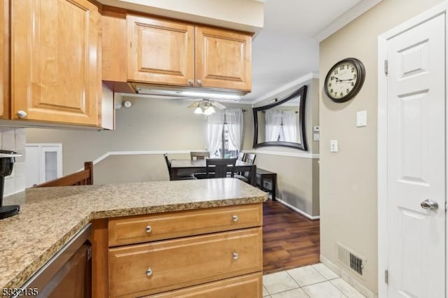 kitchen with ceiling fan, light stone countertops, kitchen peninsula, light tile patterned flooring, and ornamental molding