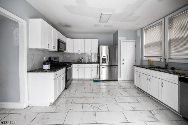 kitchen with dark stone countertops, decorative backsplash, sink, appliances with stainless steel finishes, and white cabinets