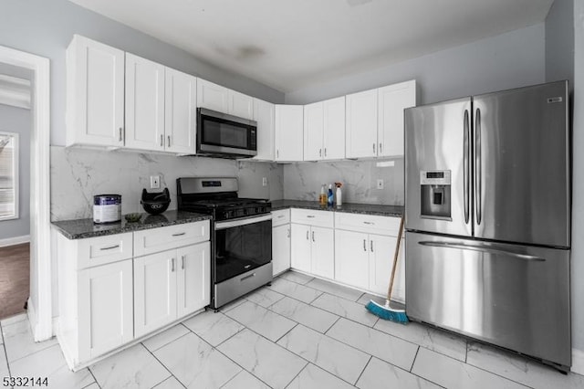 kitchen with white cabinets, appliances with stainless steel finishes, and dark stone counters