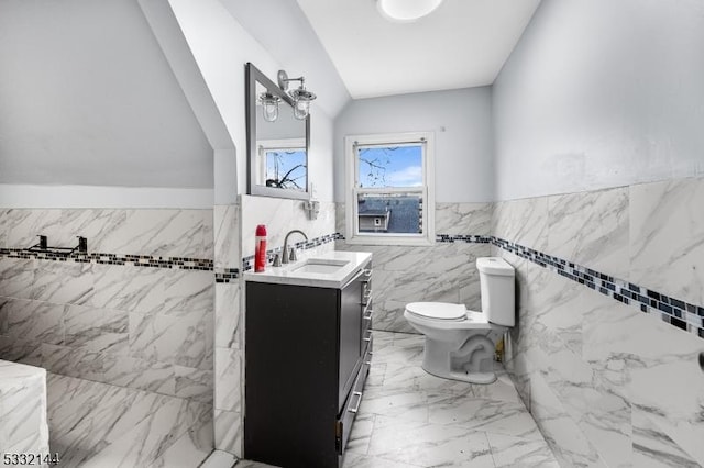 bathroom featuring toilet, vanity, tile walls, and vaulted ceiling