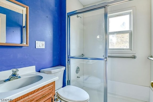 bathroom featuring a shower with door, vanity, and toilet