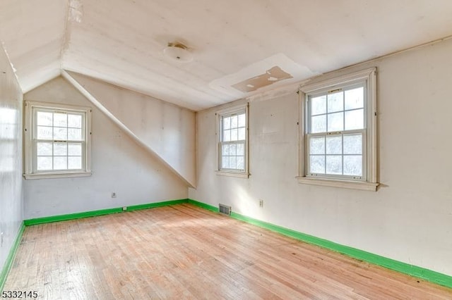 additional living space with hardwood / wood-style floors and lofted ceiling