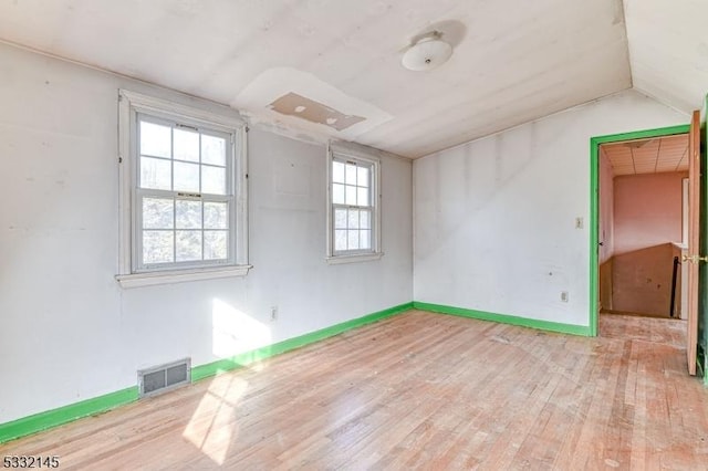 spare room with light hardwood / wood-style flooring, a healthy amount of sunlight, and lofted ceiling