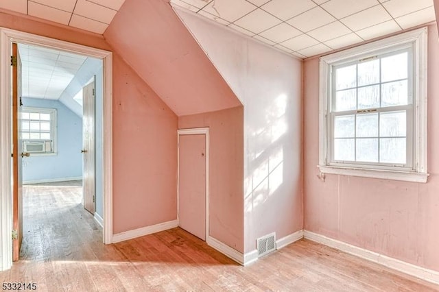 bonus room with cooling unit, light hardwood / wood-style floors, and vaulted ceiling