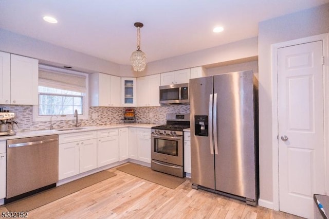 kitchen featuring appliances with stainless steel finishes, sink, white cabinetry, and pendant lighting