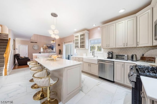 kitchen with sink, pendant lighting, a breakfast bar area, decorative backsplash, and appliances with stainless steel finishes