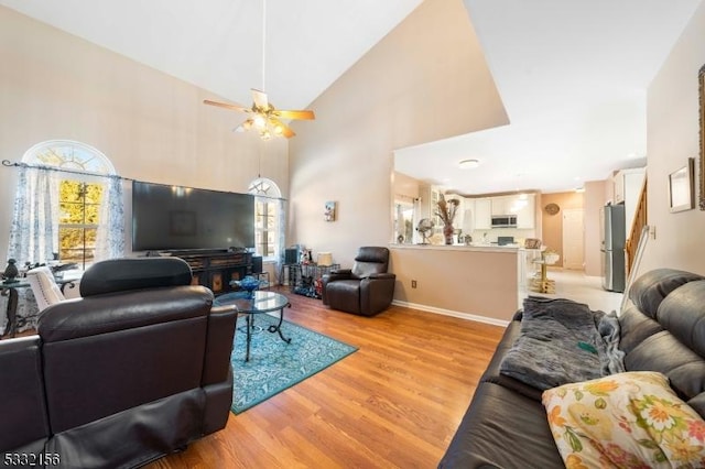 living room with ceiling fan, light hardwood / wood-style flooring, and high vaulted ceiling