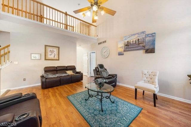 living room featuring ceiling fan, a towering ceiling, and hardwood / wood-style flooring