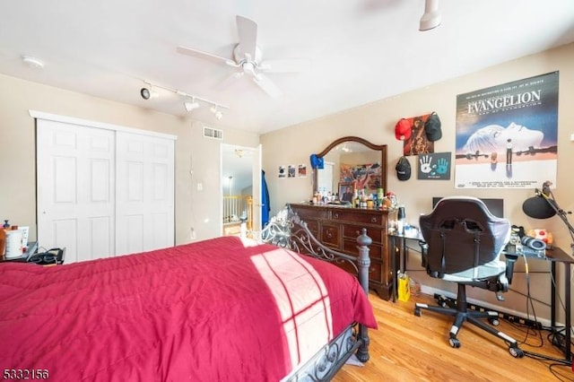 bedroom with wood-type flooring, rail lighting, a closet, and ceiling fan