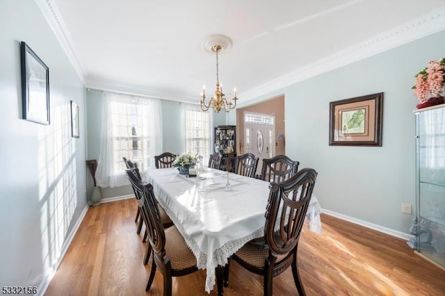 dining room with light hardwood / wood-style floors, crown molding, and a chandelier