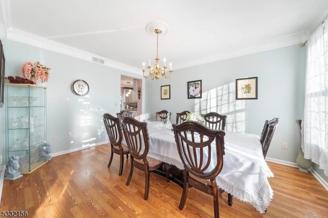 dining area featuring a chandelier, light wood-type flooring, and crown molding