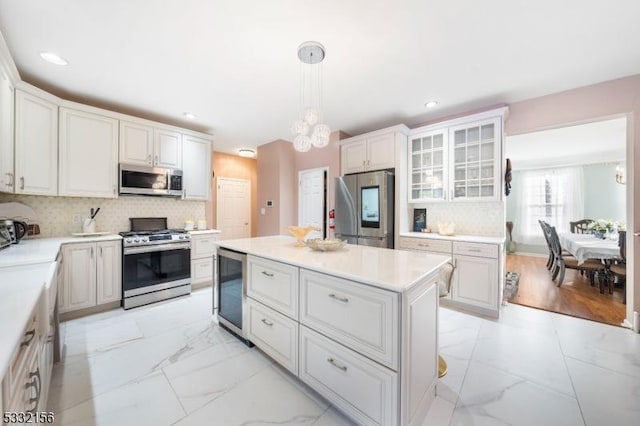 kitchen featuring backsplash, stainless steel appliances, white cabinetry, and hanging light fixtures