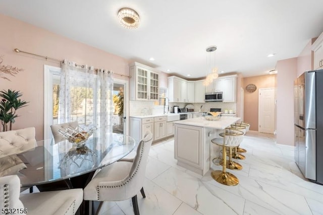 kitchen with stainless steel appliances, tasteful backsplash, decorative light fixtures, a breakfast bar, and a kitchen island