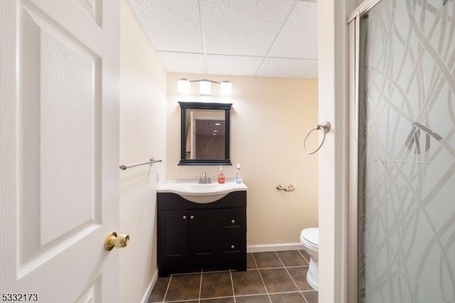 bathroom with walk in shower, tile patterned flooring, toilet, a paneled ceiling, and vanity