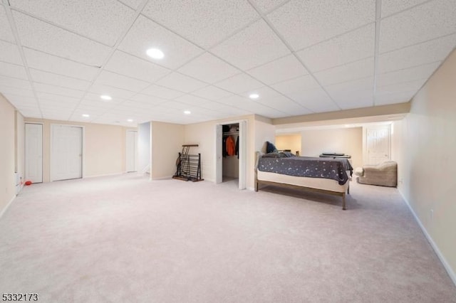 carpeted bedroom with a drop ceiling and a closet