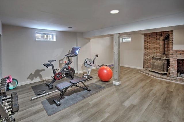 exercise area with light wood-type flooring and a wood stove