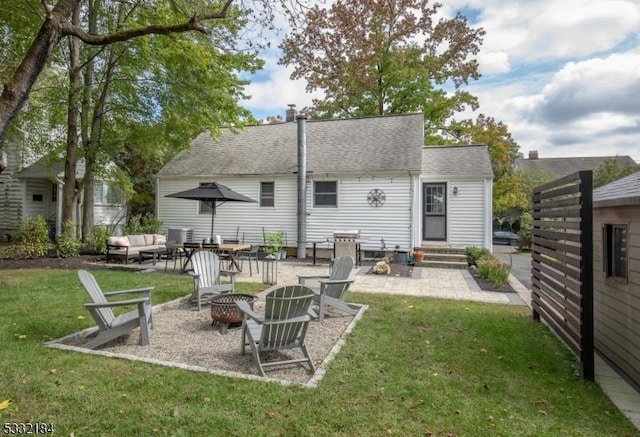 rear view of house with an outdoor fire pit, a patio area, and a lawn