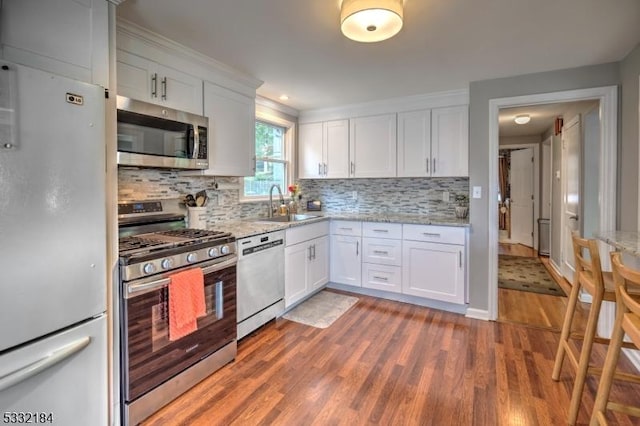 kitchen featuring stainless steel appliances, white cabinets, sink, and hardwood / wood-style flooring